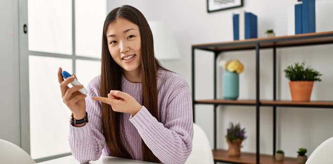 A woman smiles, while testing her glucose reading